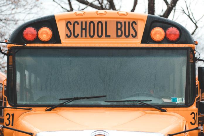A close up shot of the front of a school bus - only the hood and the front windshield are visible.