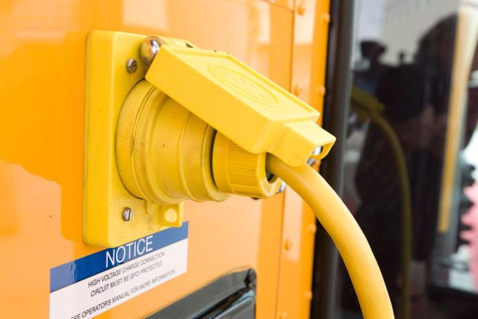 A charging port for an electric school bus is plugged into the bus.