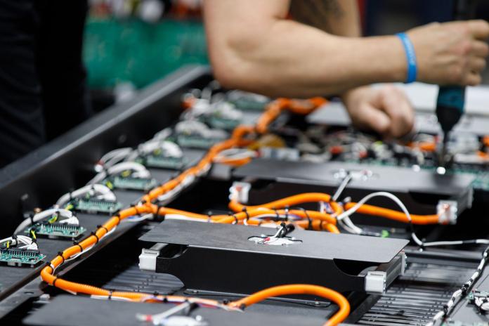 A person works on the type of battery often used in electric school buses.