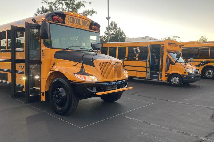 Three electric school buses parked in a lot.
