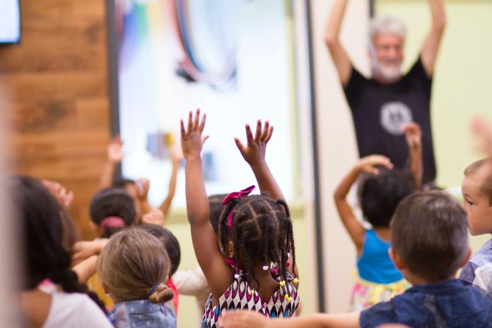 Young students raise their hands in a classroom.