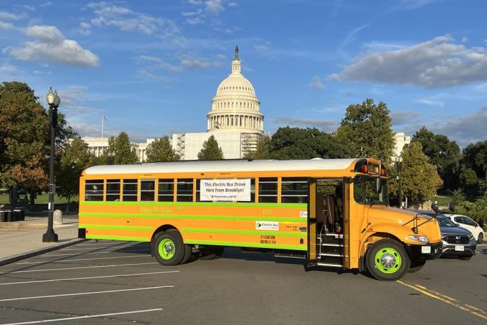 An electric school bus in a parking lot near the US Capitol building.