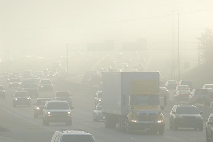 Smog over a highway with cars and trucks.