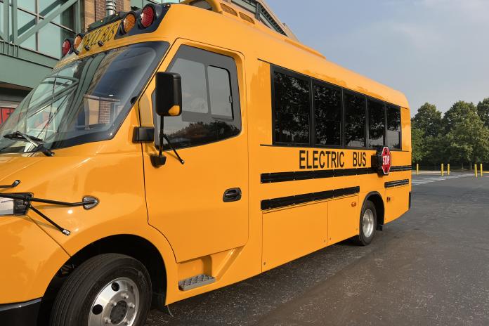 A Type A electric school bus parked in a parking lot.