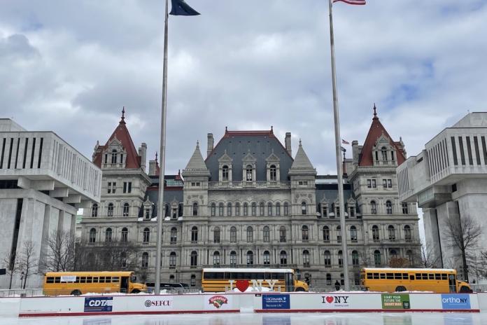 Electric school buses in front of the state capitol of New York.