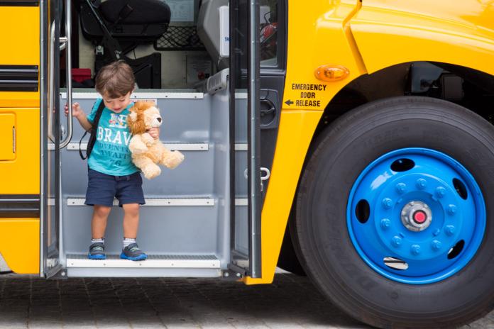 Young student deboarding a school bus