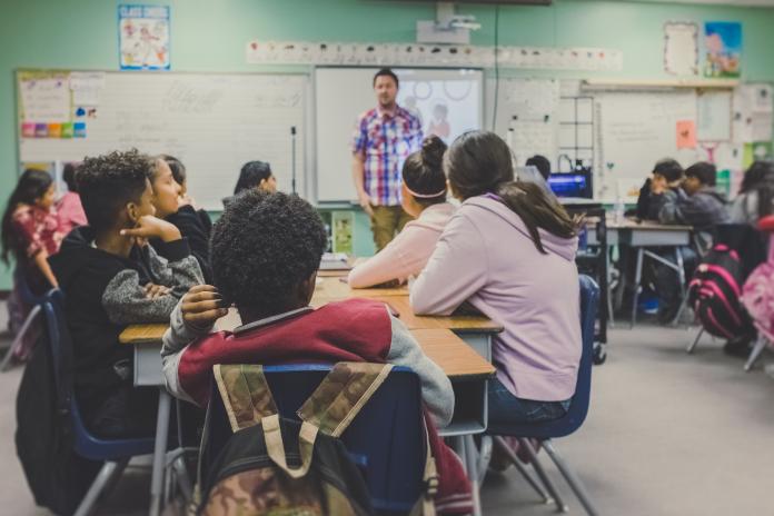 Student sit at desks in a classroom.