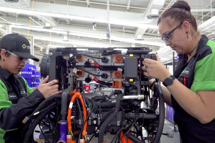 Workers assemble an electric school bus powertrain.