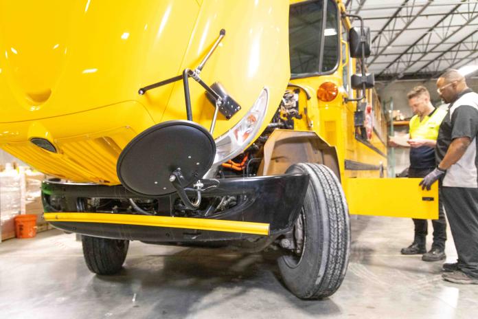 SEA Electric technicians work on an electric school bus