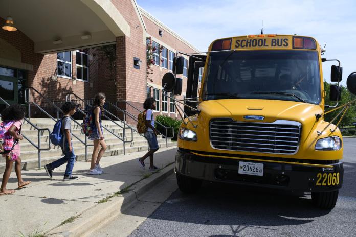Students board an electric school bus