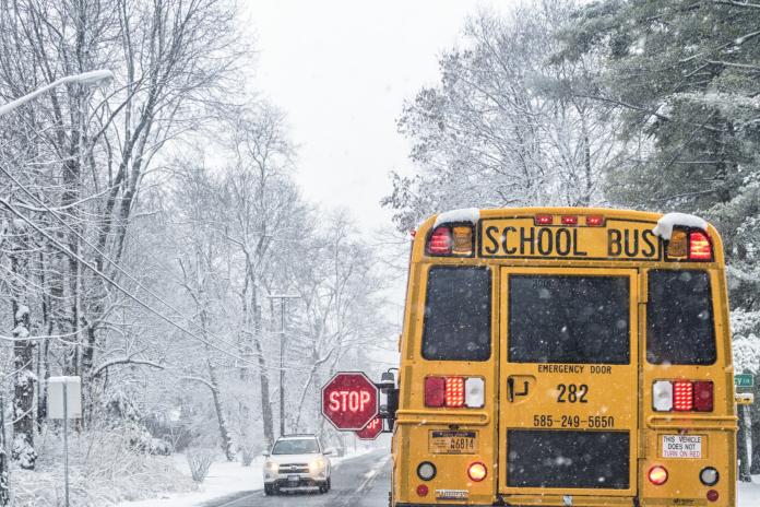 A school bus drives in the snow.