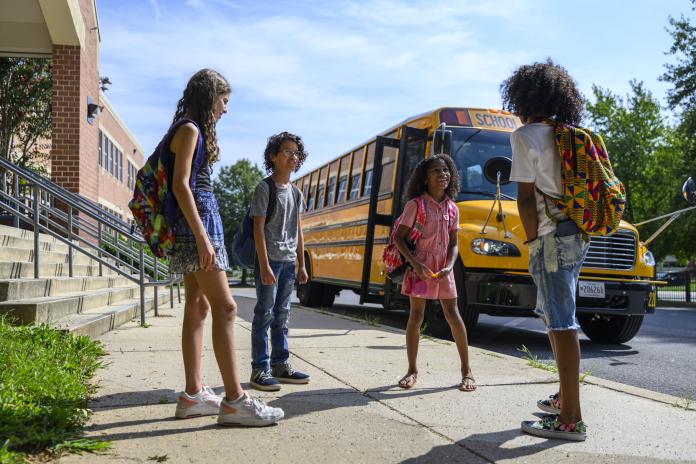 Students talking next to an electric school bus