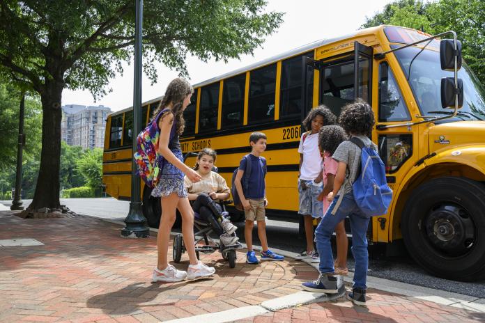 Students gather near an electric school bus. 