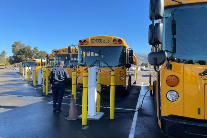 Electric school buses charging in a lot. 