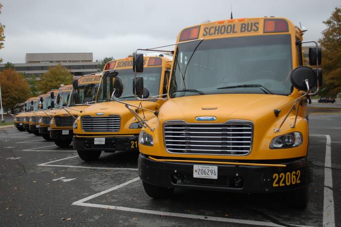 Row of electric school buses in parking lot
