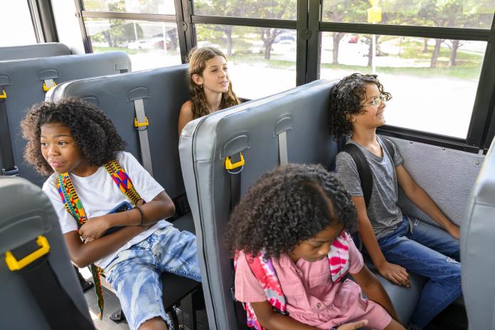 Four students sit on an electric school bus.