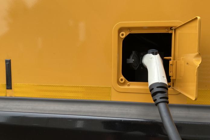 Close up shot of an electric school bus charger plugged into the bus charging port