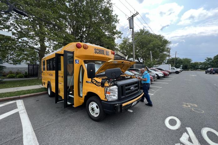 Type A electric school bus from NYCSBUS in New York City with a worker and open hood.