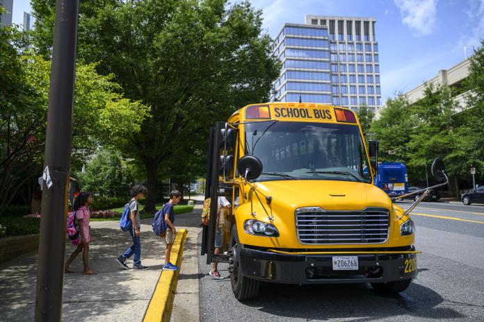 Students boarding an electric school bus. 
