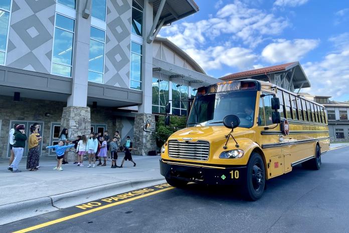 Students standing near an electric school bus.