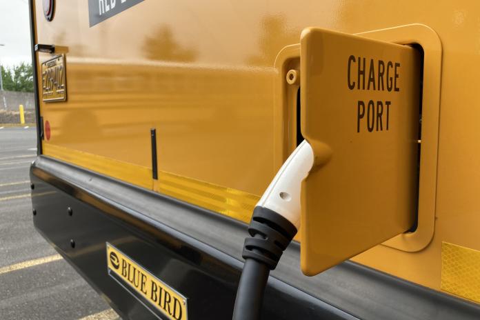 A close up photo of a charger plugged into yellow school bus