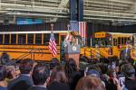 Vice President Kamala Harris speaks at a lectern in front of two electric school buses.
