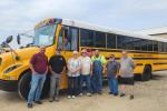 A group of people stand in front an electric school bus in Williamsfield, Illinois