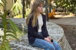 Girl sitting on wall made of rocks looking into distance.