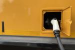 Close up shot of an electric school bus charger plugged into the bus charging port