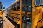 An electric school bus charges while parked under the sun