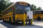 Electric school bus charging in parking lot. 