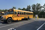 An electric school bus charges in a parking lot
