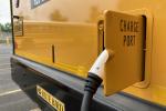 A close up photo of a charger plugged into yellow school bus