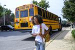 Student with backpack near back of electric school bus