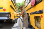 A driver plugs in an electric school bus.