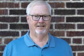 Headshot of a person in front of a brick wall, John Wiles