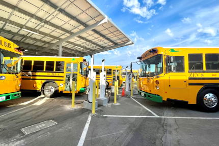 Electric school buses charge in a parking lot.