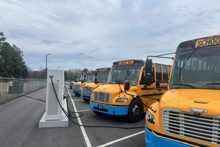 Electric school buses charging in a school bus depot.  