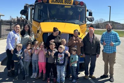 Students and Sipayik Elementary School Administrators in front of one of their electric school buses.