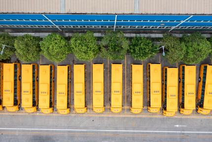 Electric school buses in a parking lot, seen from overhead.