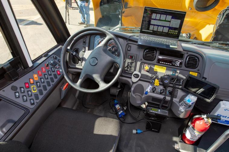Photo of an electric school bus dashboard, featuring the steering wheel and a collection of buttons to the left of the steering wheel.
