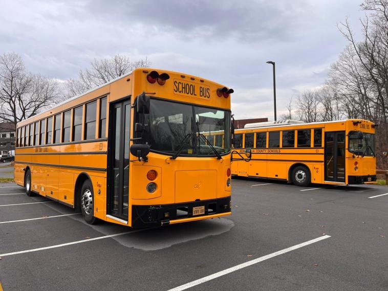 Electric school buses parked in a parking lot.