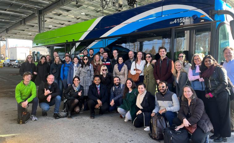 ESB Initiative staff stand in a group, smiling in front of an electric transit bus.