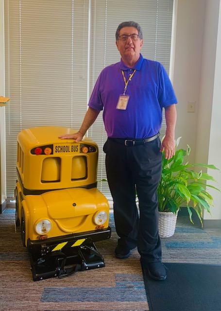 Kris Hafezizadeh stands next to a school bus toy in an office.