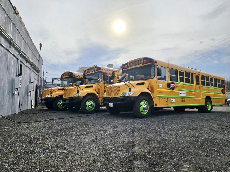 Three repowered electric school buses charging.