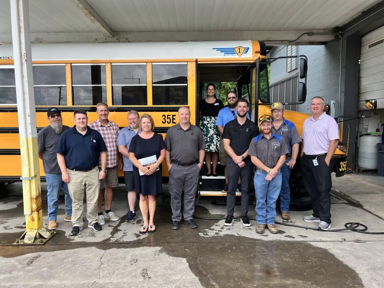People stand near an electric school bus.