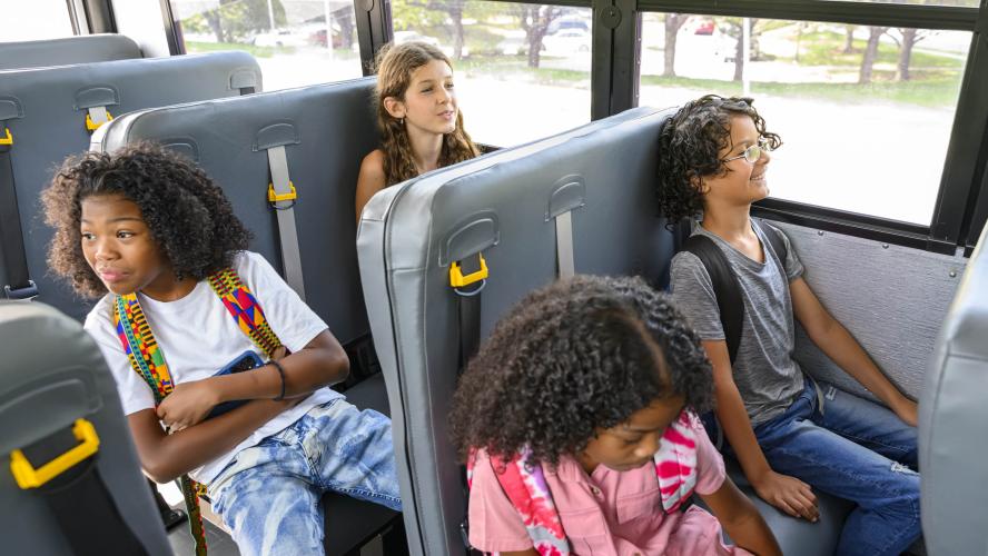 Four students sit on an electric school bus. 