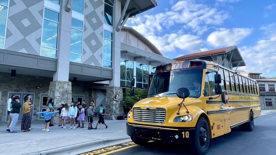 Students standing near an electric school bus.