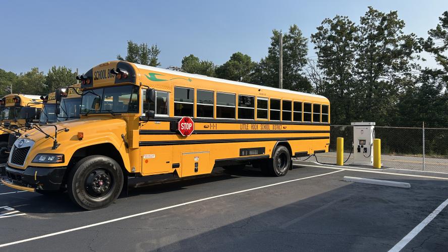 An electric school bus charges in a parking lot