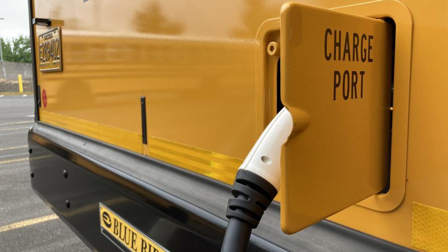 A close up photo of a charger plugged into yellow school bus